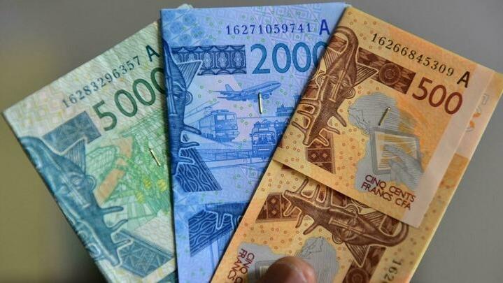 A picture taken on September 12, 2017 shows franc CFA banknotes. – A controversial west African activist, Kemi Seba, was expelled from Senegal following an incident last month in which he burned 5,000 CFA francs — a banknote worth 7.6 euros ($9.10) — in an anti-colonial protest over « French Africa ». The CFA franc is pegged to the euro and used in 14 African countries, six of which are former French colonies. (Photo by ISSOUF SANOGO / AFP)