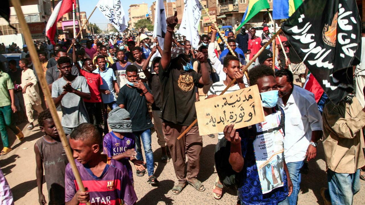 Sudanese demonstrators take to the streets of the capital Khartoum as thousands protest against the army’s October 25 coup, on December 30, 2021. The placard reads in Arabic: « Civilian or eternal revolution ». – Demonstrators reached within a few hundred metres (yards) of the presidential palace in Khartoum, headquarters of military chief General Abdel Fattah al-Burhan, before troops, police and paramilitary units launched multiple tear gas canisters into the crowd. (Photo by AFP)