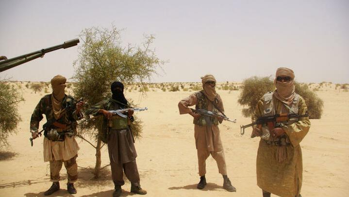 FILE – In this Tuesday, April 24, 2012 file photo, fighters from Islamist group Ansar Dine stand guard during a hostage handover in the desert outside Timbuktu, Mali. Allied Islamist groups Ansar Dine and the Movement for Unity and Jihad in West Africa, or MUJAO, are applying strict Shariah justice across the northern half of Mali, which fell to the al-Qaida-linked rebels five months ago. In the latest and most horrific incident, on Monday, Sept. 10, 2012, MUJAO carried out five double amputations, cutting the right hands and left feet off five cousins accused of highway robbery. (AP Photo/File)