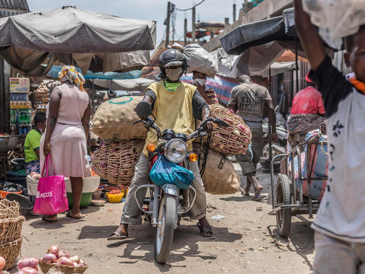 A motorcycle taxi carries bags of onions at the Dantokpa Market, the largest open-air market in West Africa, on April 20, 2020. (Photo by Yanick Folly / AFP)
