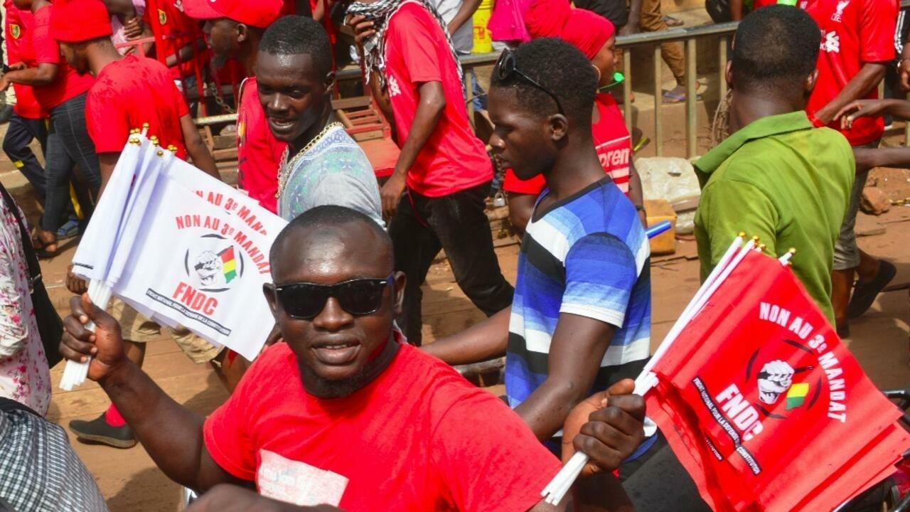A man holds flags of the National Front for the Defence of the Constitution (FNDC) reading « No to the 3rd term » on January 6, 2020 in Conakry, as he takes part in an anti-government rally to protest against President Alpha Conde plans to stay in office for a third term. – Thousands of Guineans took to the streets on January 6, in a new anti-government protest, with partisan violence injuring at least 12 people in the country’s east. (Photo by CELLOU BINANI / AFP)